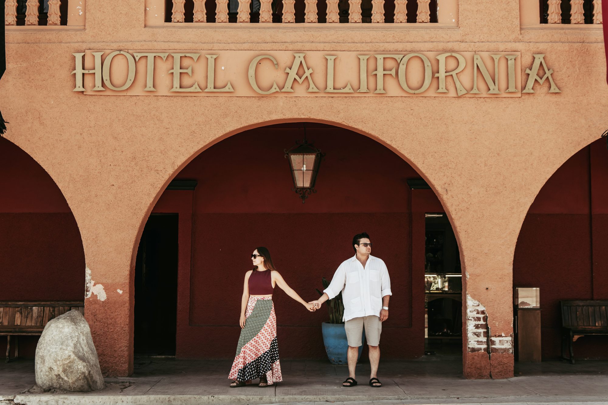 Couple holding hands under the Hotel California arches in Todos Santos — David Lack